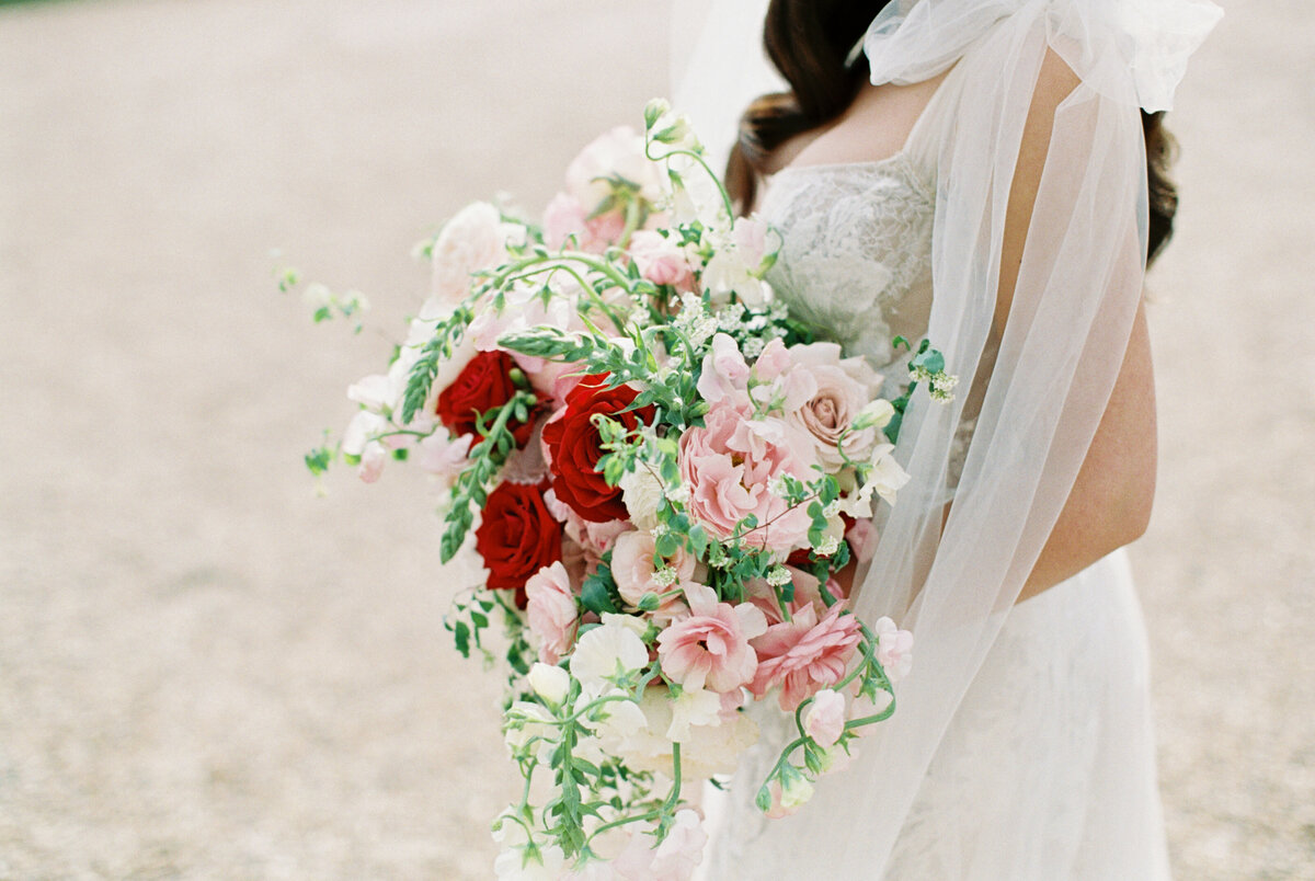 bride holding red and blush pink wedding bouquet