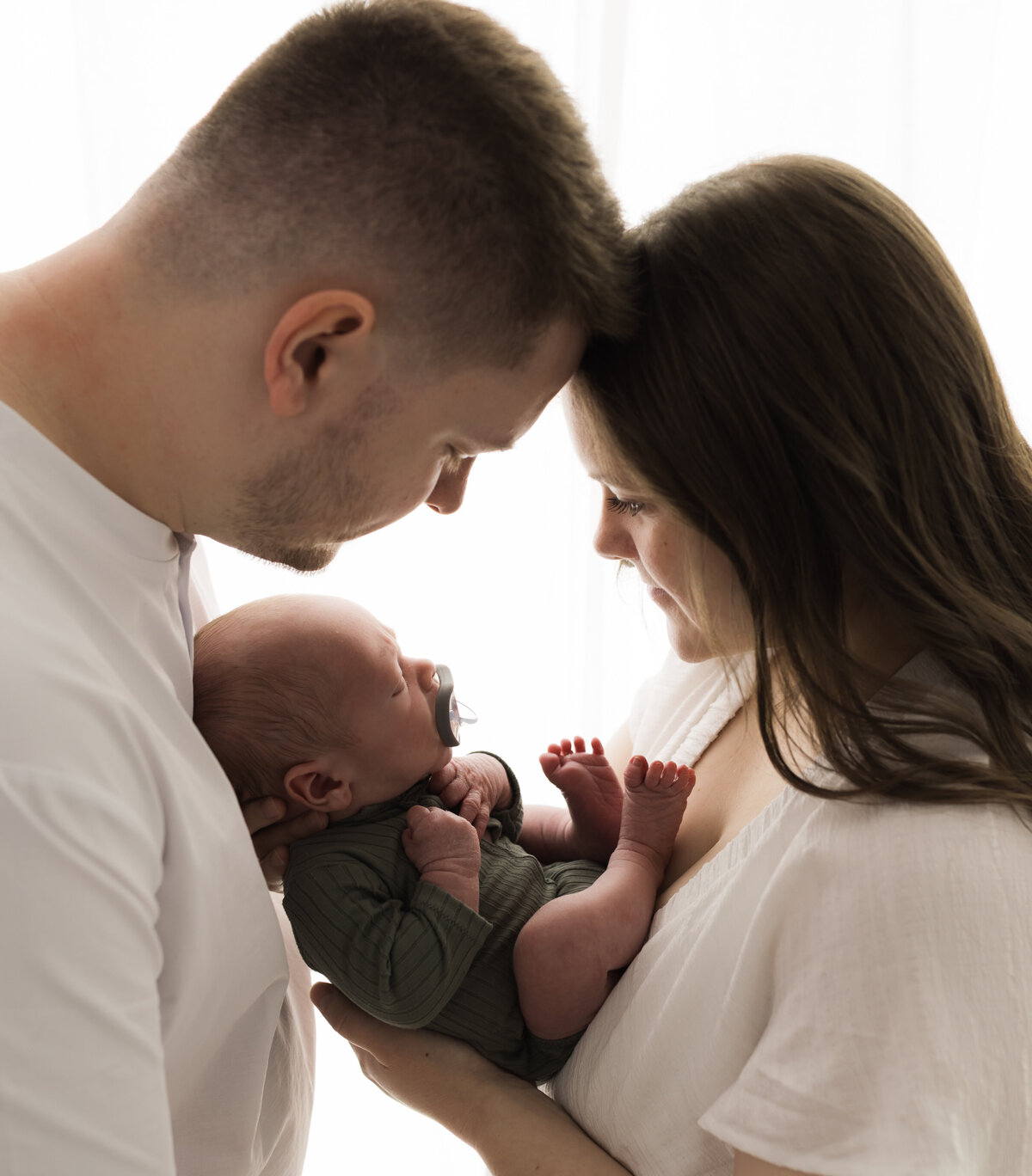 mom and dad holding newborn baby boy in green onesie