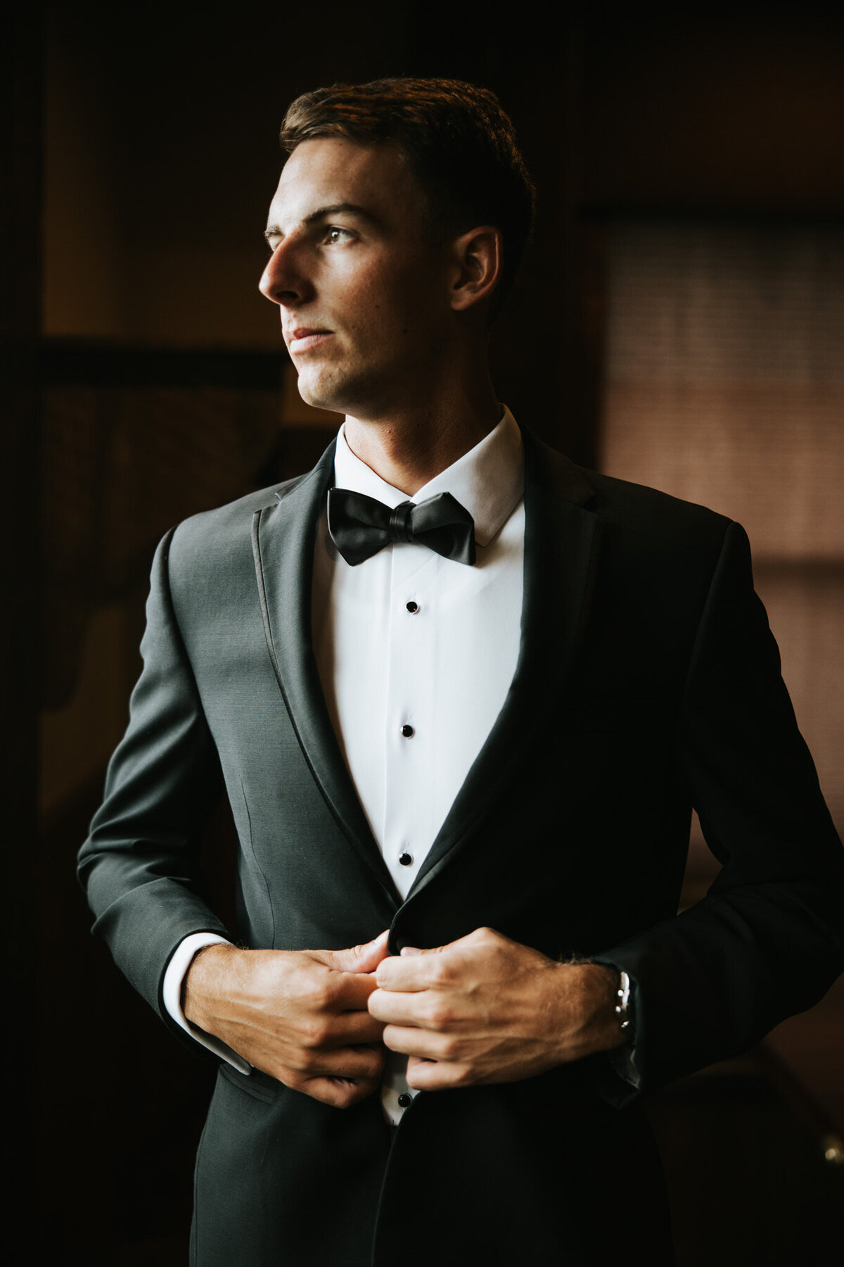 Groom looking out the window, reflecting before the wedding ceremony.