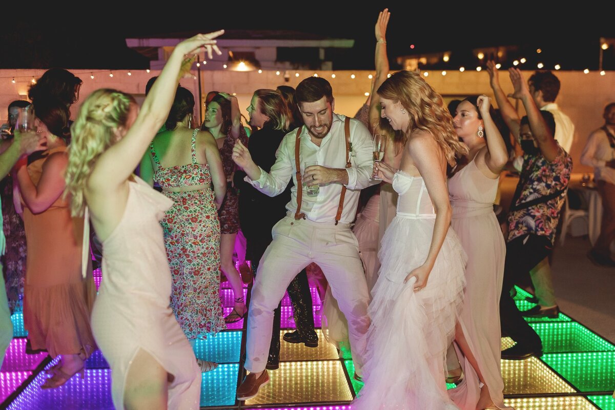 Guests dancing with bride on lite dancefloor at wedding in Riviera Maya.