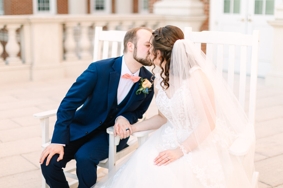 CNU Alumni and Wedding Photographer captures the bride and groom who met at Christopher Newport University and then were married there, they kiss on the rocking chairs where they had many dates