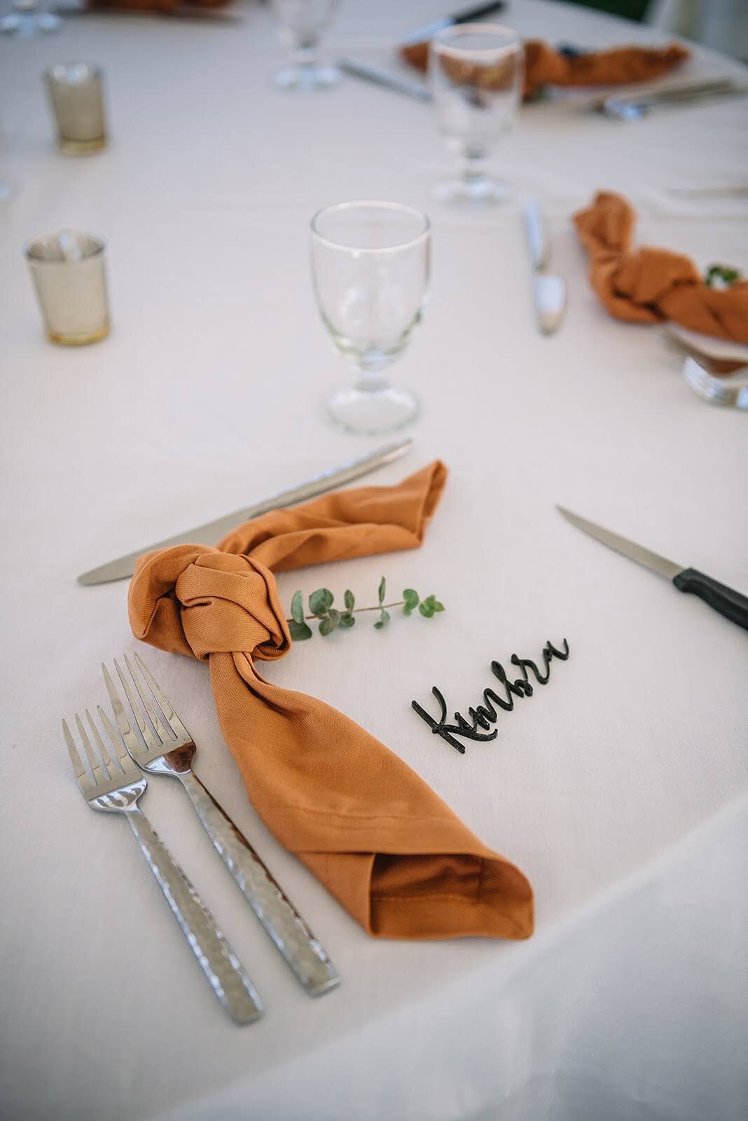 Orange napkin with acrylic  name placec ard at a wedding in Colorado.