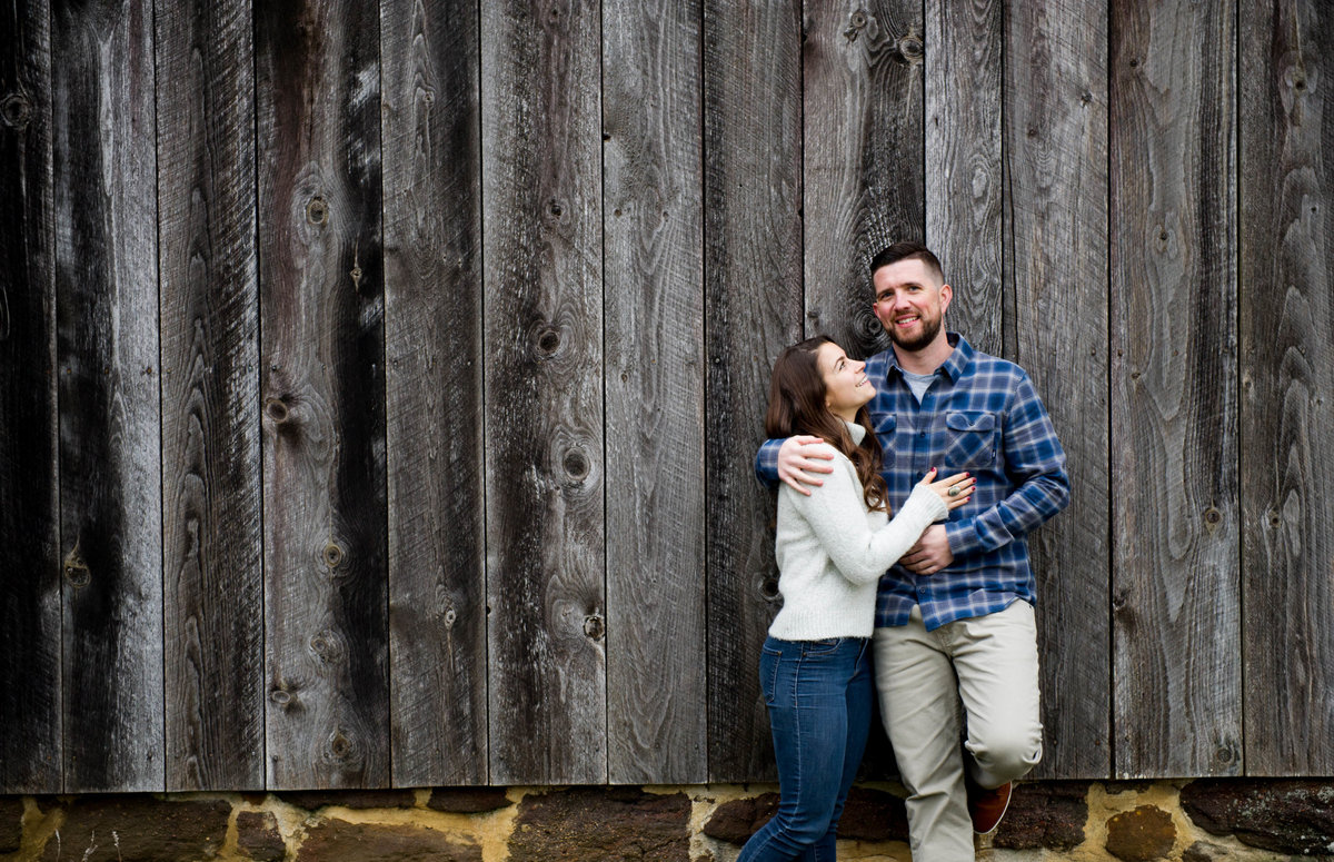 couple lean against weathered barn