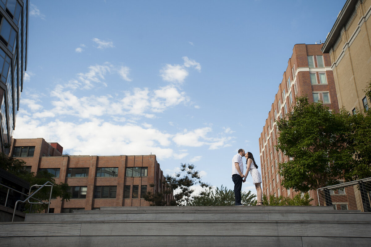 A couple holding hands and kissing at the top of a staircase 