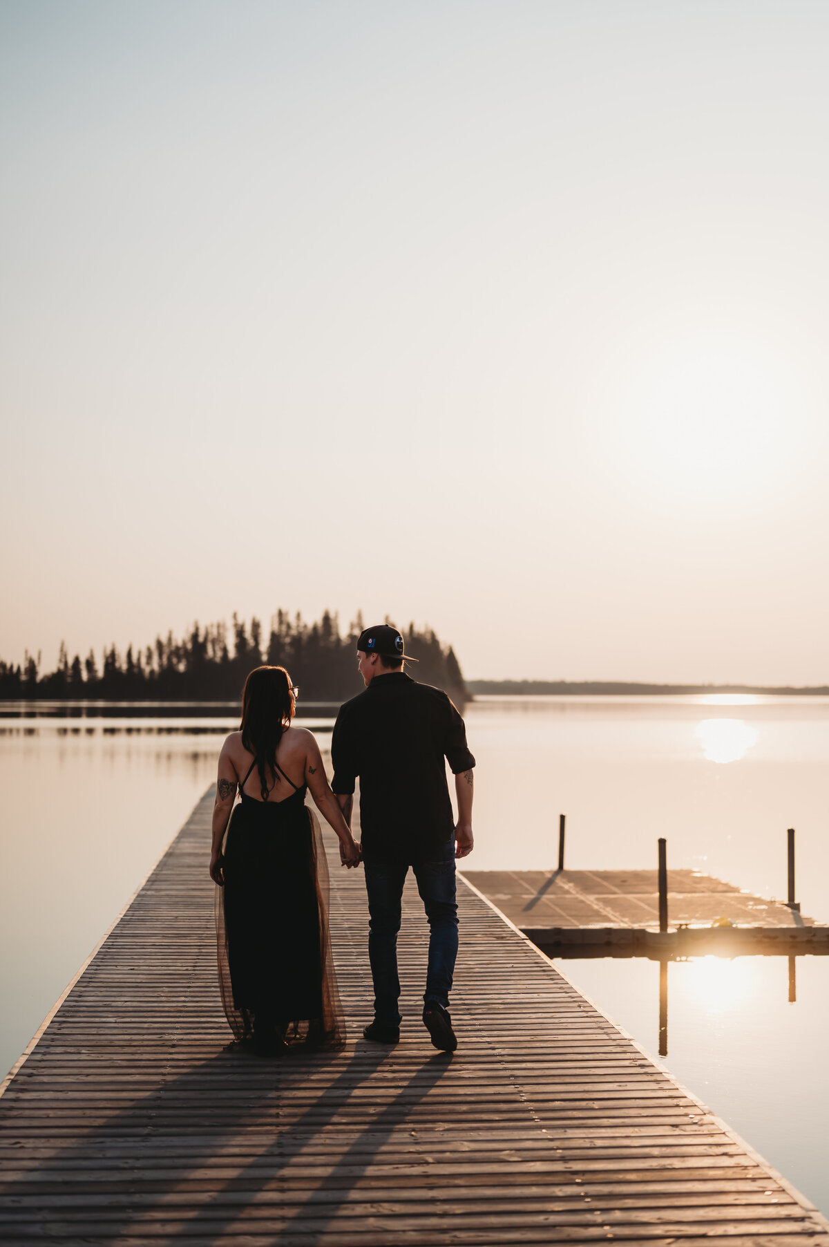 engaged couple walking on boardwalk hand in hand