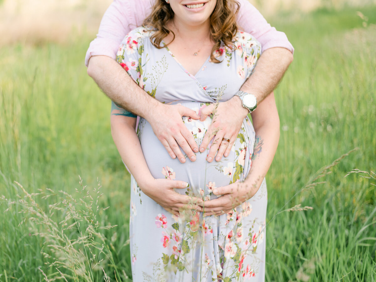 Close up photo of expecting parents holding growing belly..