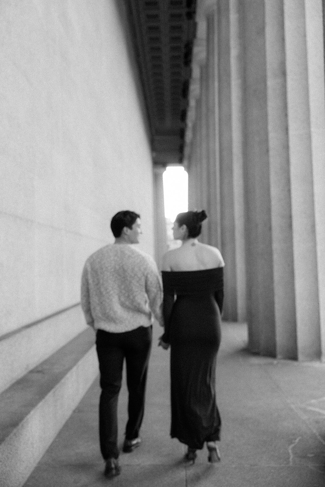 Couple walks hand in hand along the pillars of the Parthenon in Nashville, TN after getting engaged. 
