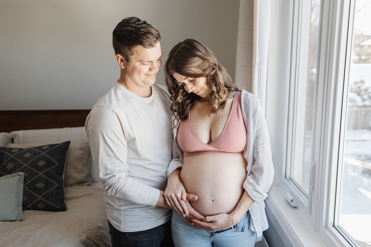 Pregnant woman and husband portrait next to bedroom window