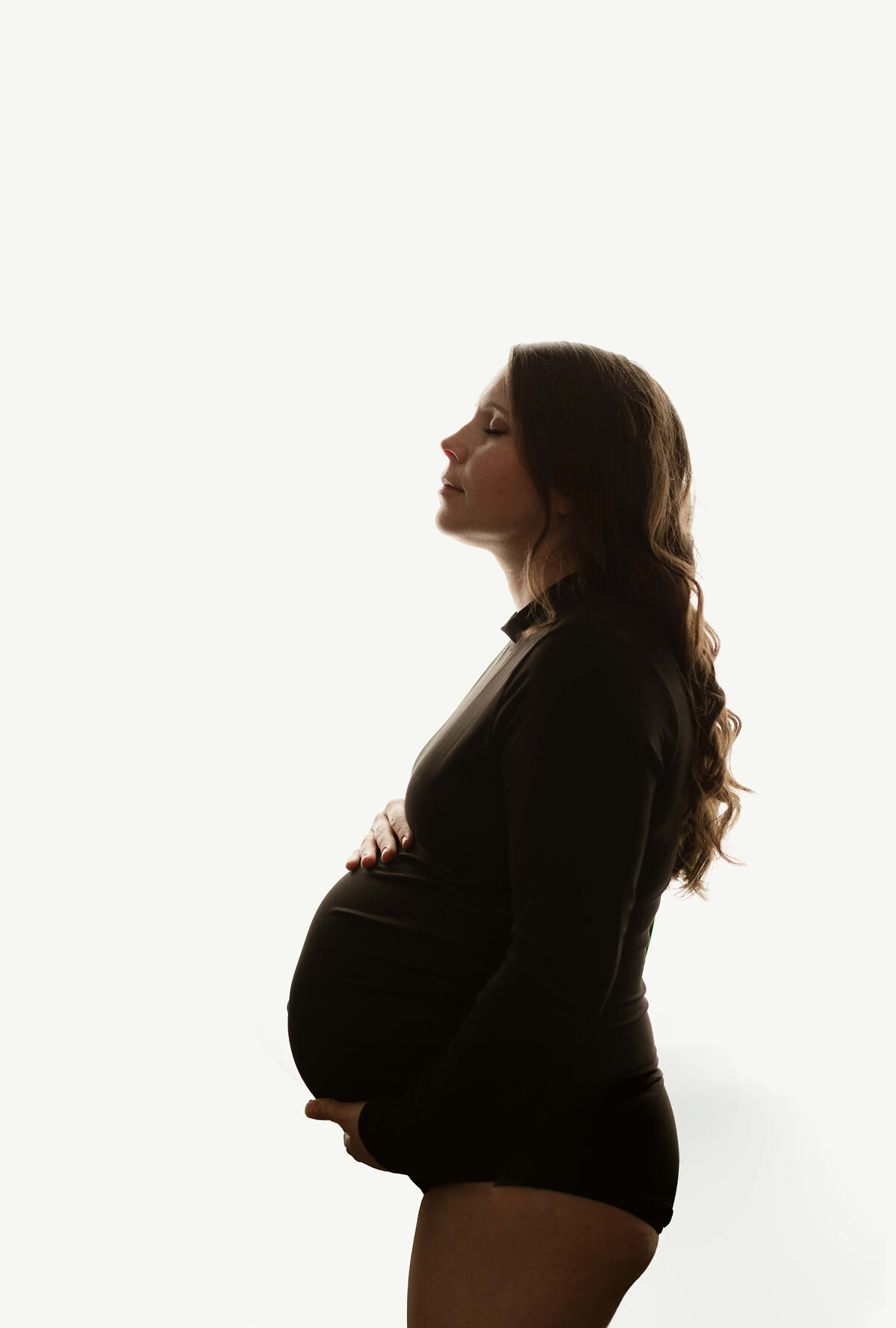 Side profile silhouette of pregnant woman in black bodysuit on white background