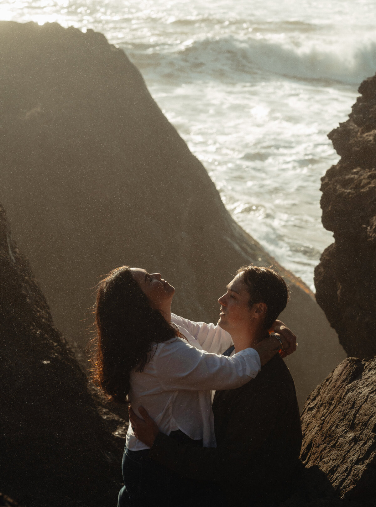 lifestyle engagement photo of couple watching the waves with arms around each other on the Oregon coast