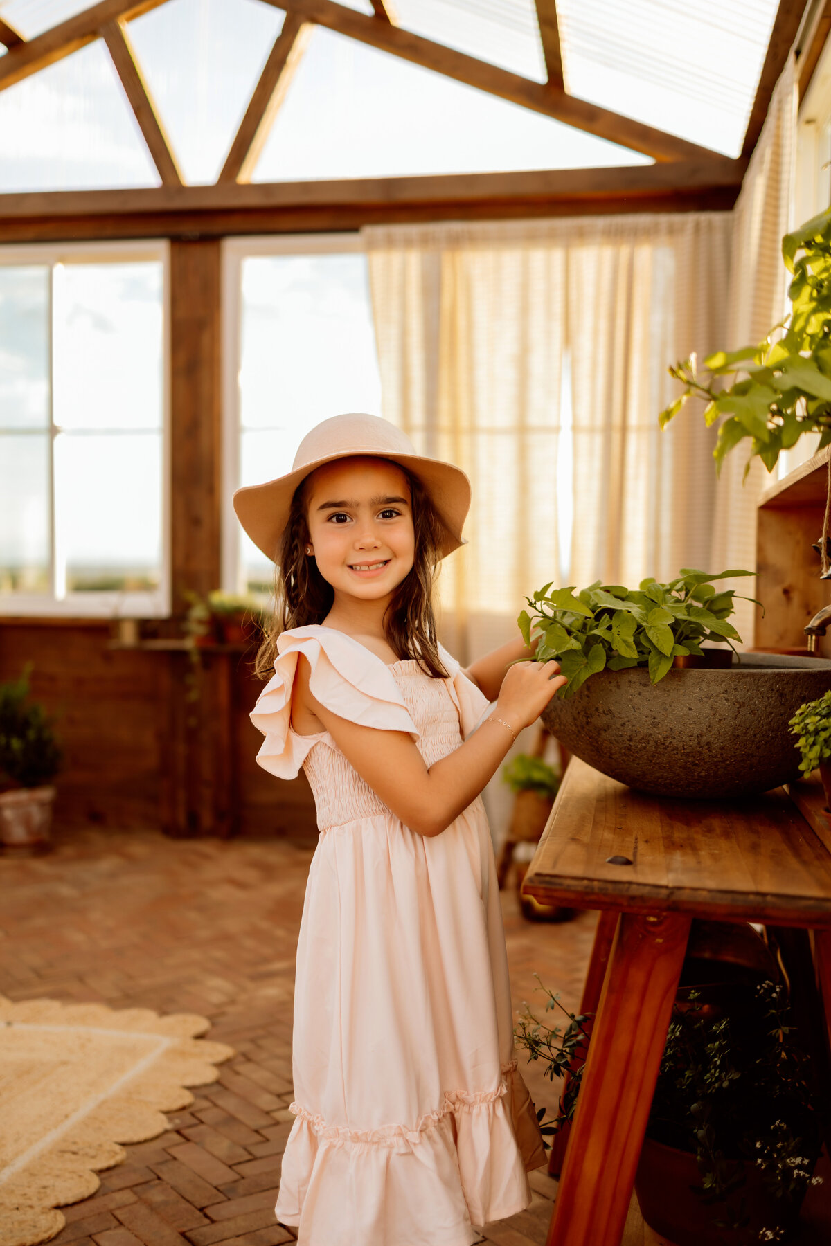 Young girl pots plants in a greenhouse for Denver family pictures