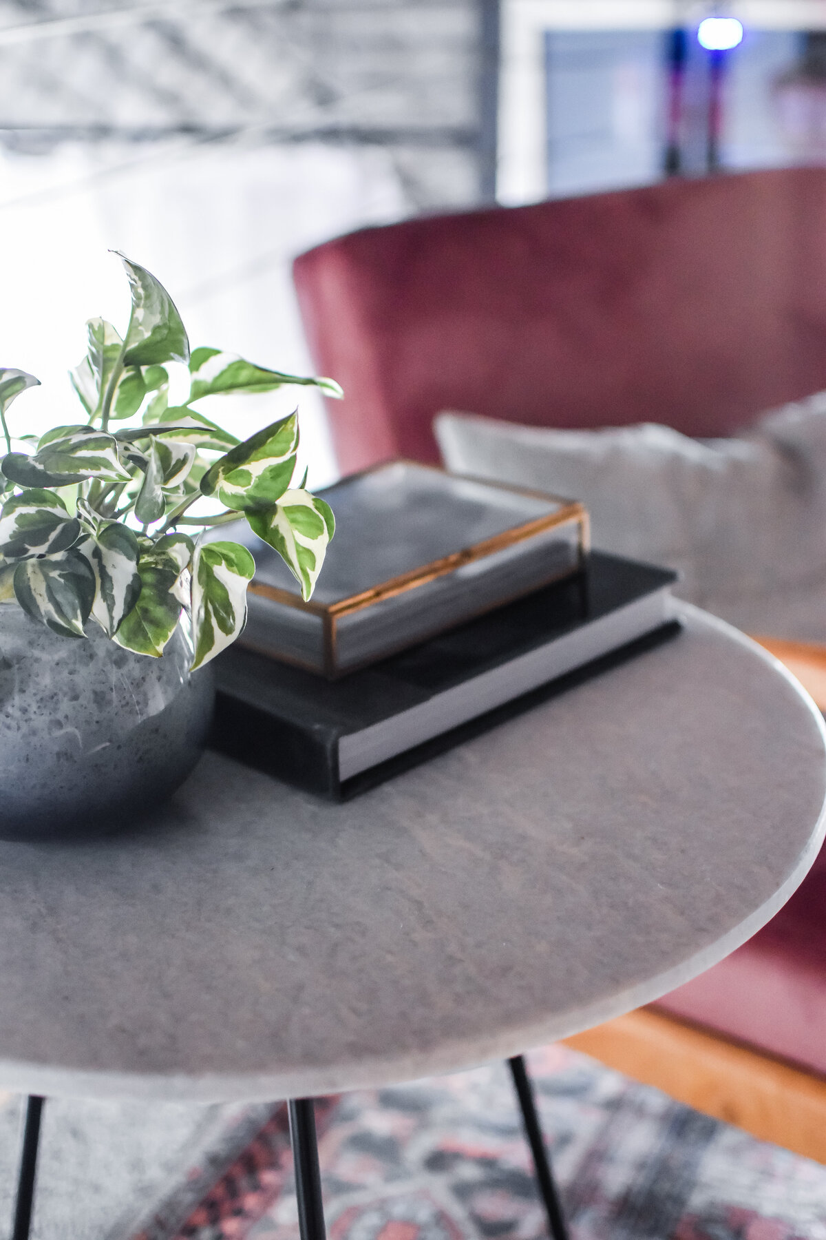 A pothos plant sits on a small white marble end table
