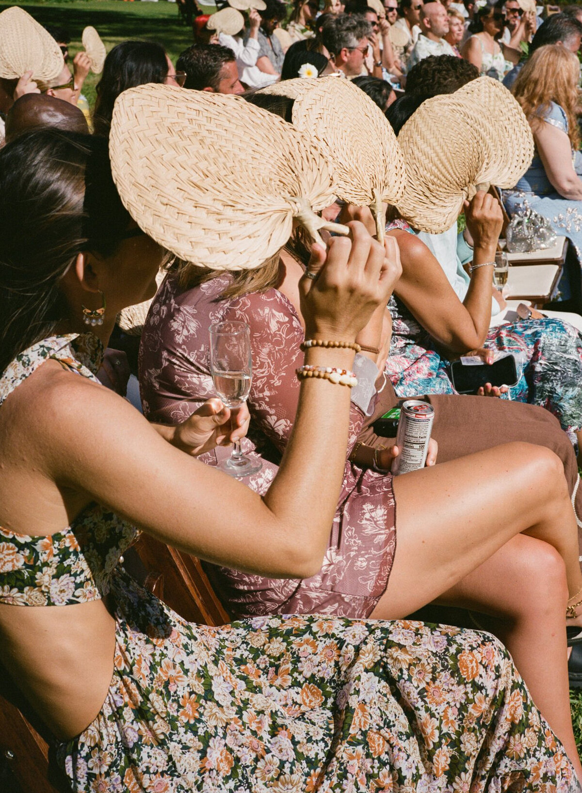 A nostalgic film detail of guests fanning themselves during a Hawaiian wedding ceremony, capturing the warmth and atmosphere through Kate Winters’ documentary lens