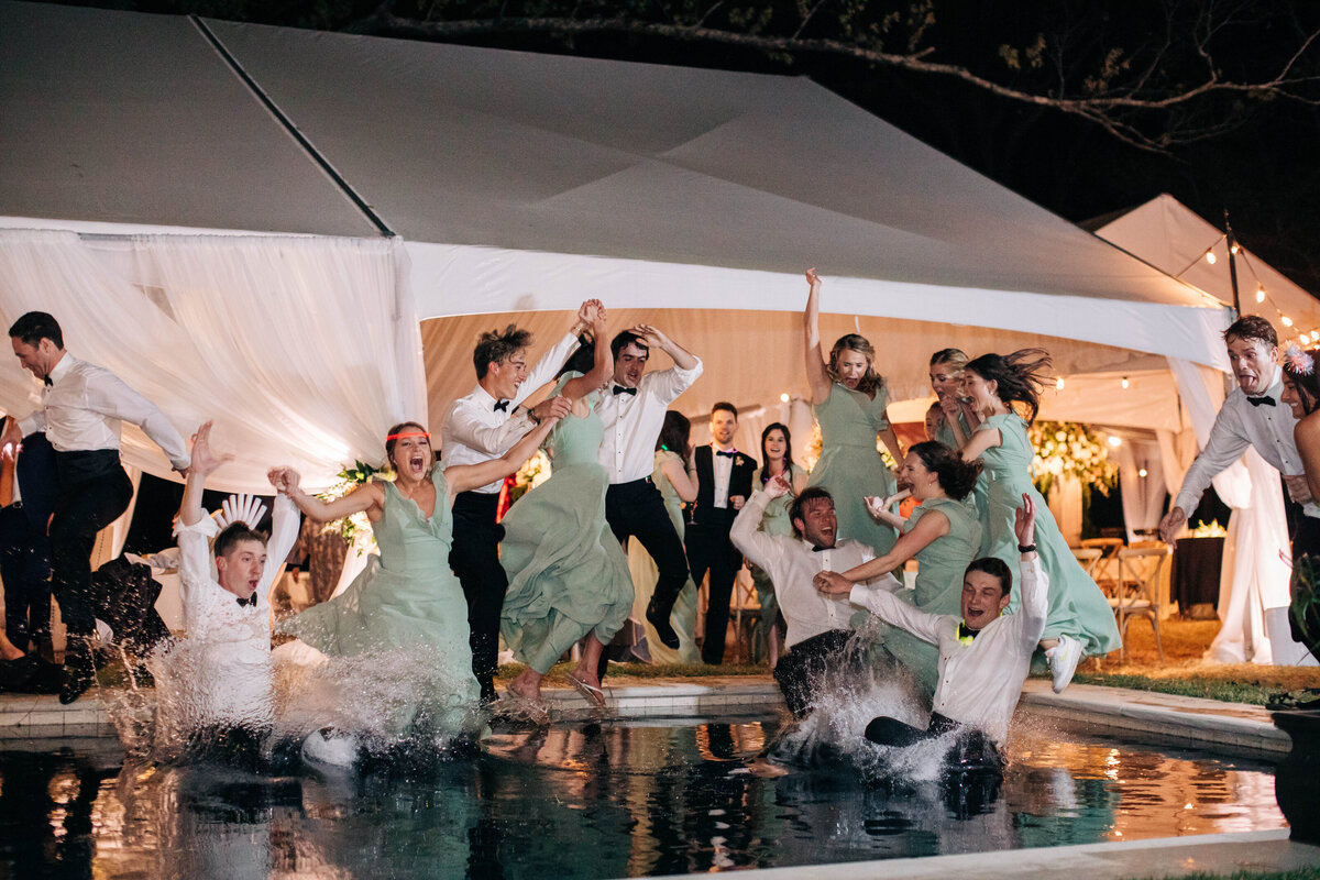 Wedding guests jumping into a pool at wedding reception