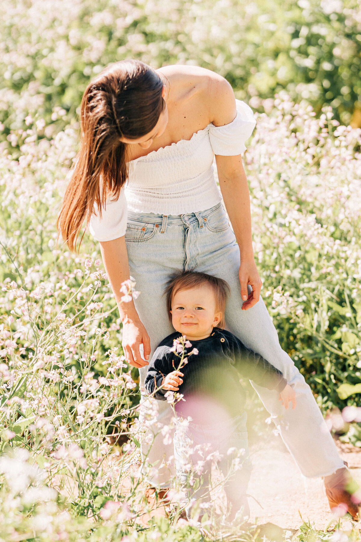 mom wearing puff sleeve white top and baby navy sweater at the wildflower field
