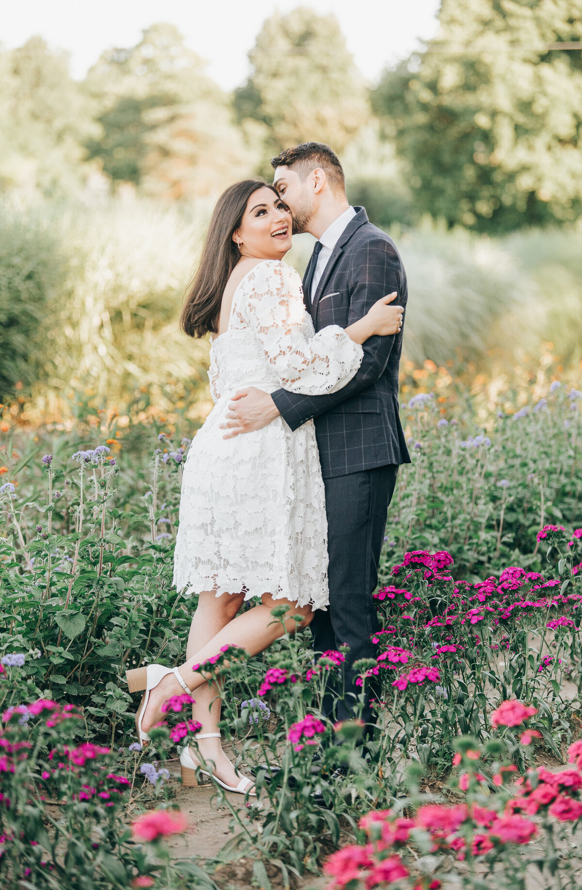 Couple posing for engagement photos in  a whimsical wildflower field during their Summer engagement session