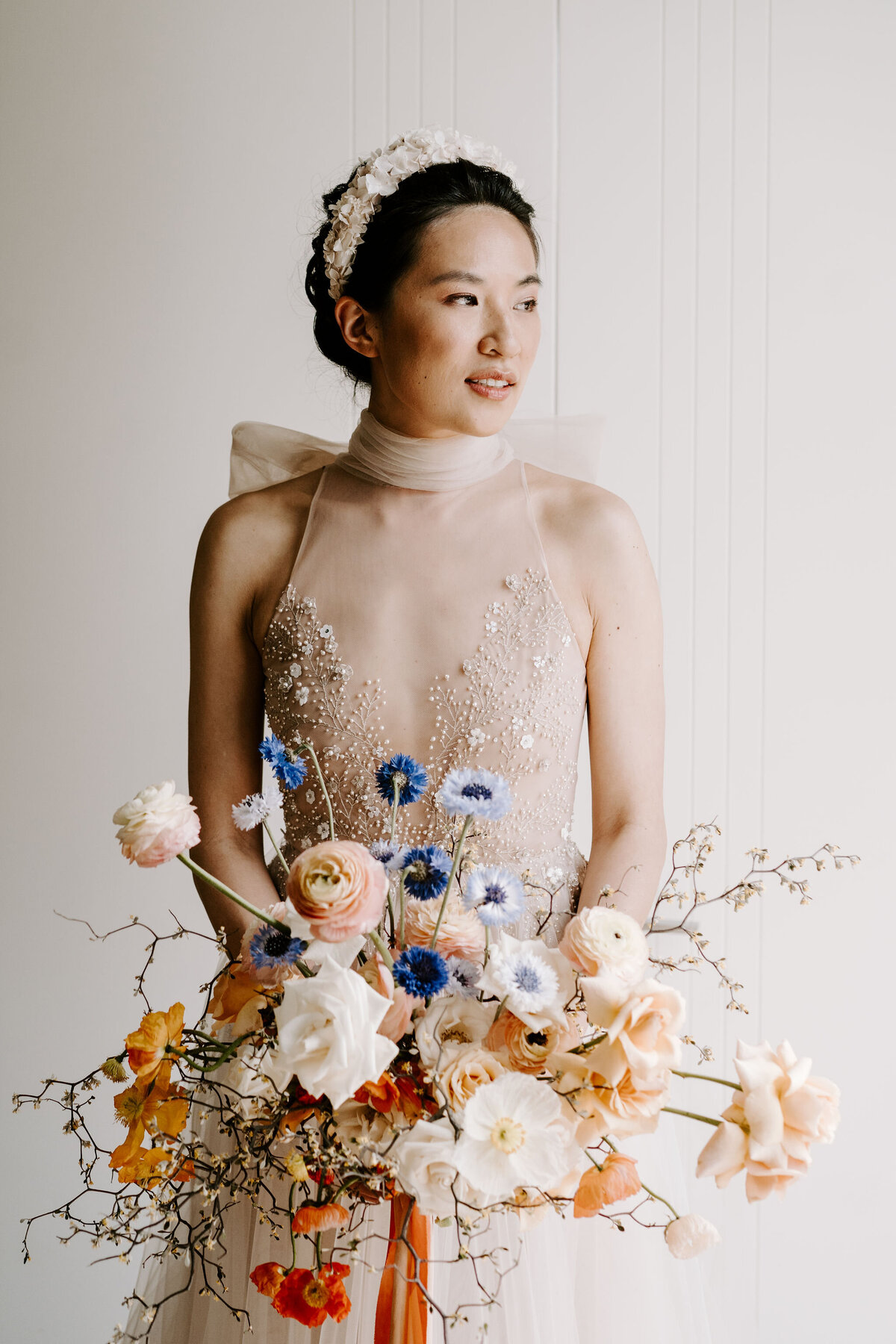 Bayonet Peak heli wedding bride holds colourful spring bouquet and wears a bespoke flower headpiece create by The Vase Floral Co for The Lovers Elopement Co