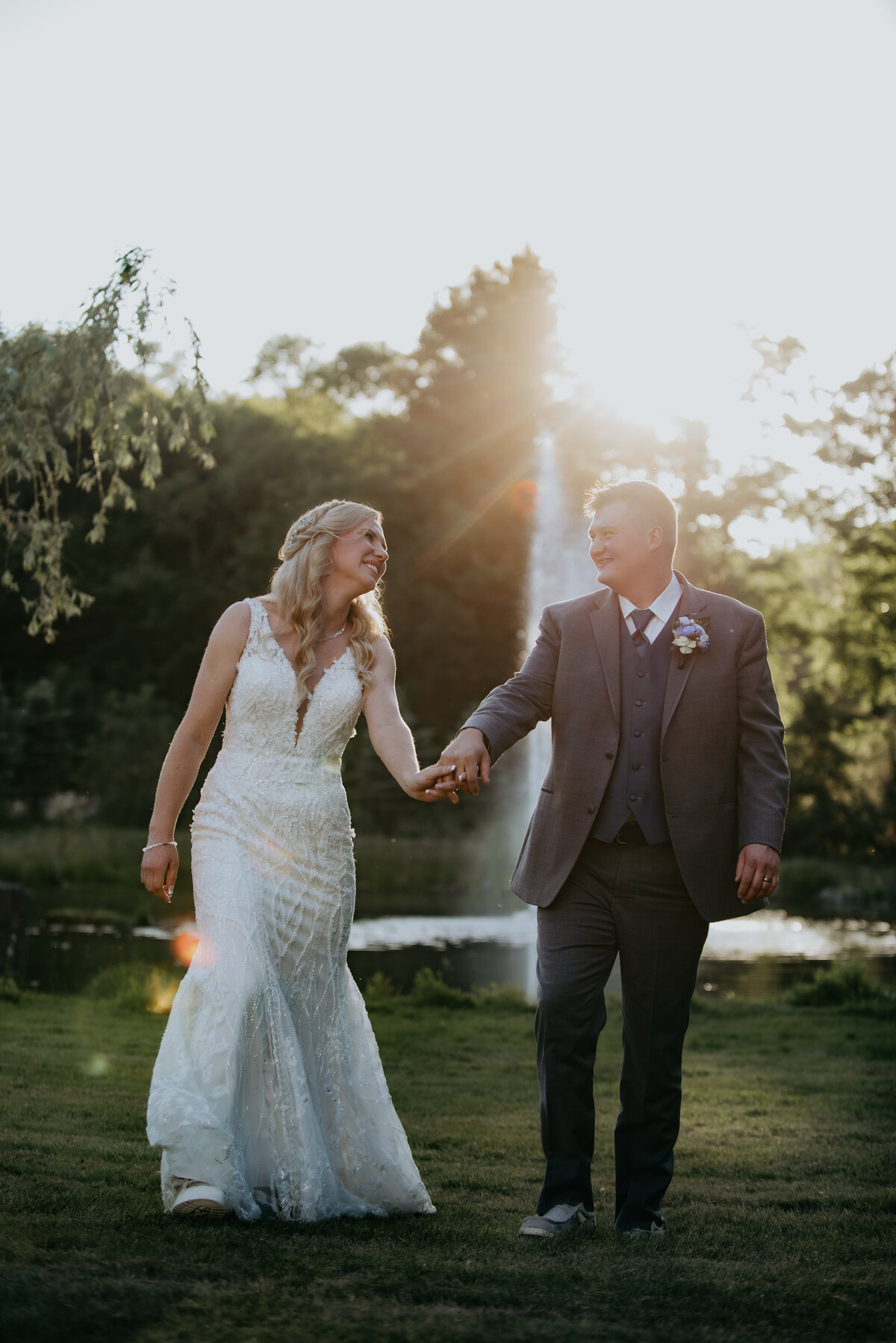 Golden hour with a bride and groom on their wedding day walking and laughing in front of a lake and geyser.