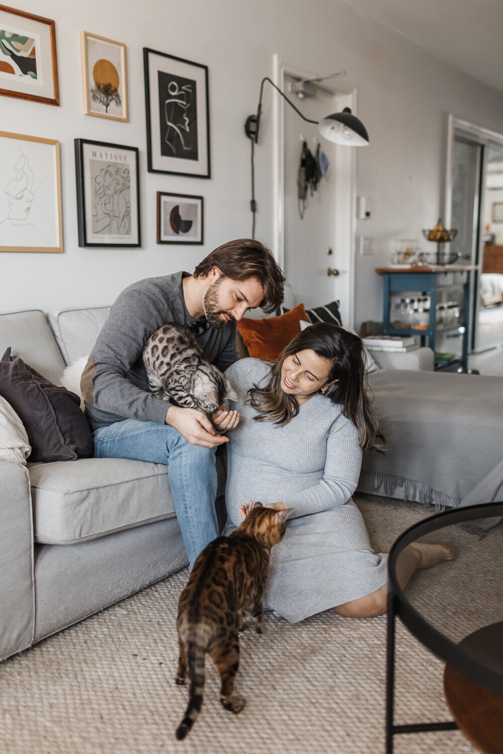 Expecting couple posing with their two cats during their at home maternity session by Claire Binks Photography