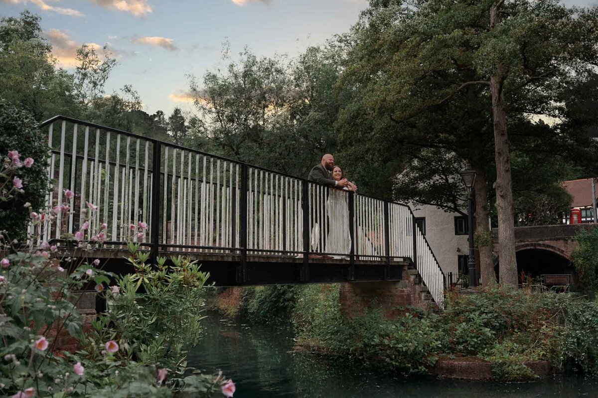 Bride and groom embracing on a bridge at Worsley Court wedding.