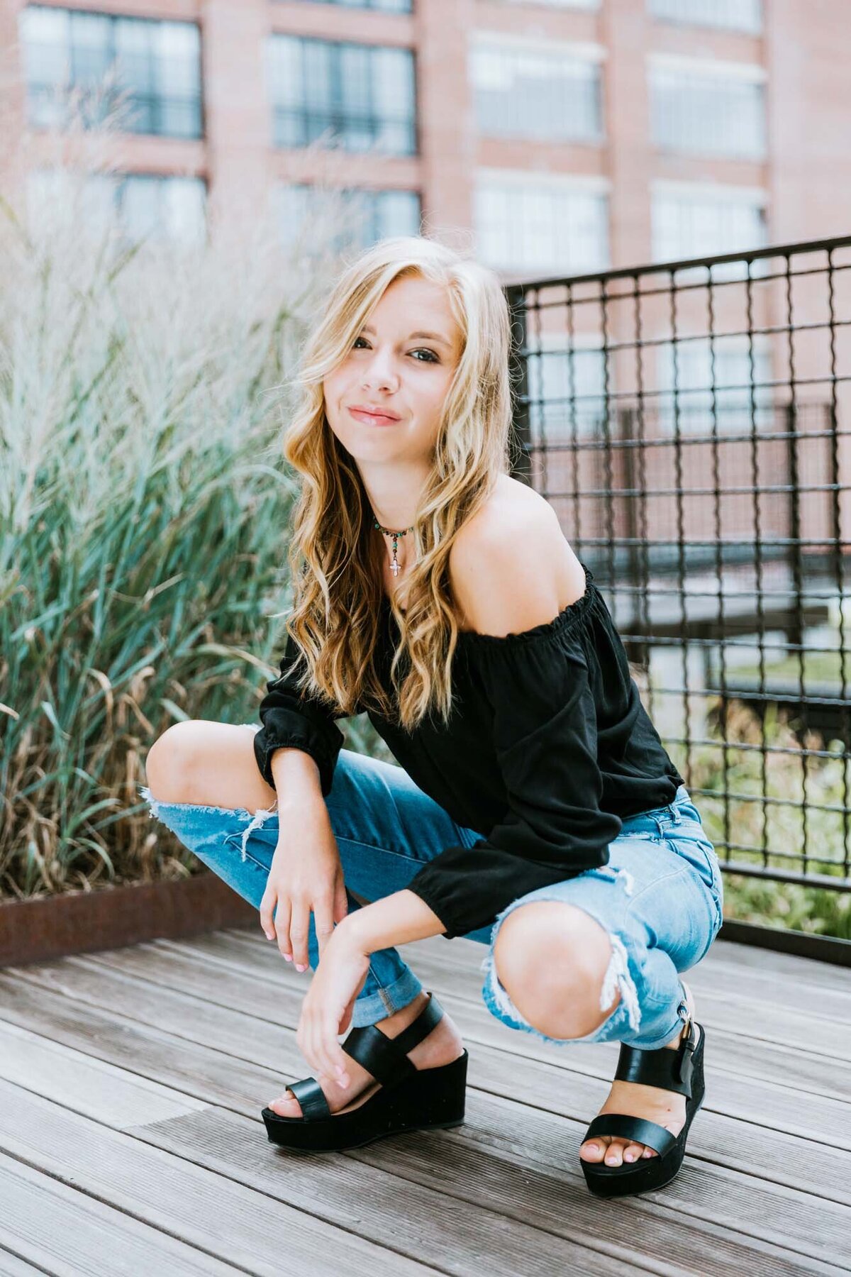 An urban senior portrait of a girl in ripped jeans and a black shirt