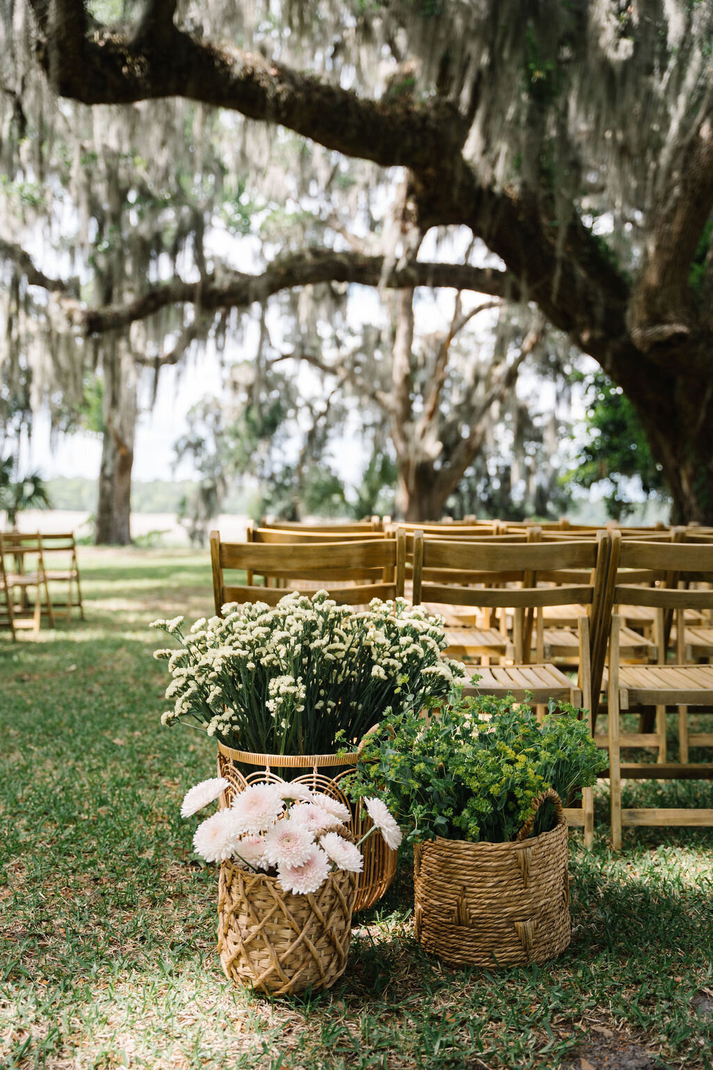 Baskets of flowers sitting next to wedding ceremony chairs