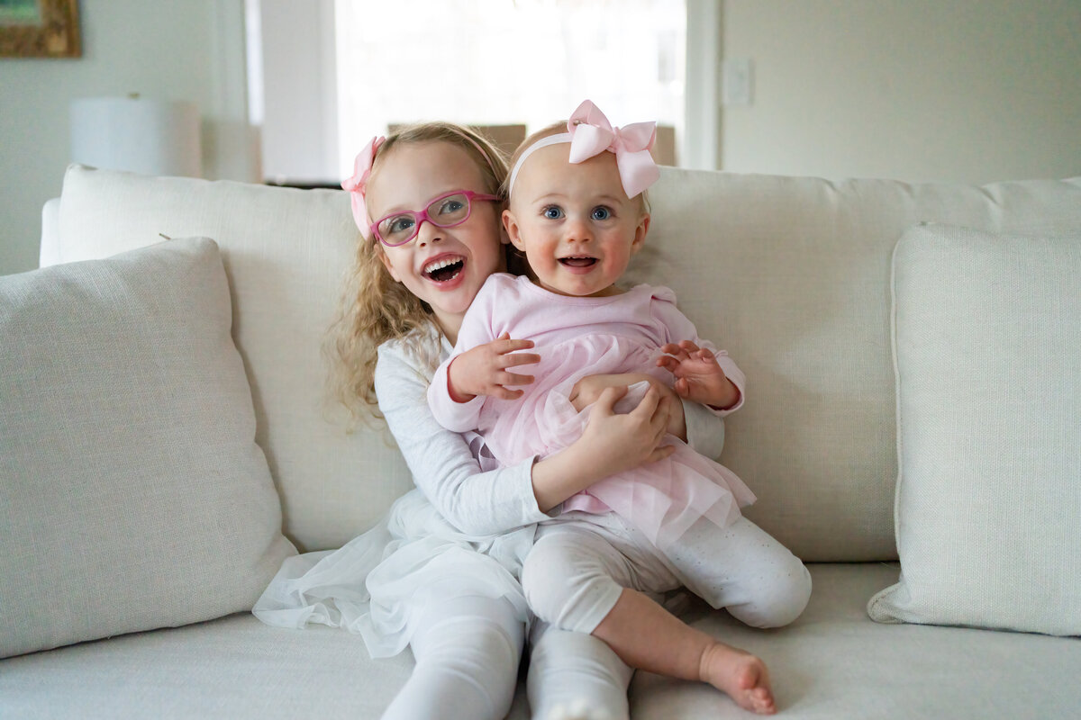 Little sister sitting on big sister's lap during Wayland MA in home family session