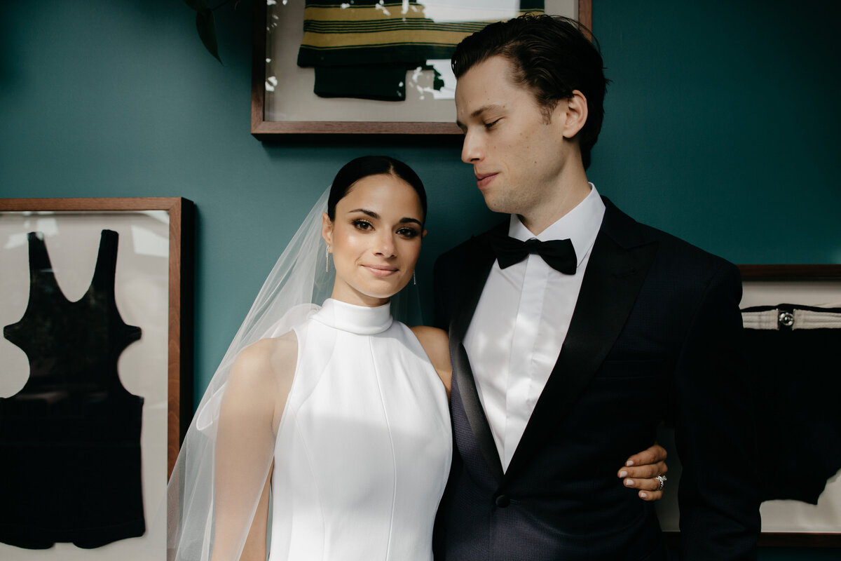 Bride and groom stand against gallery wall after downtown Chicago first look