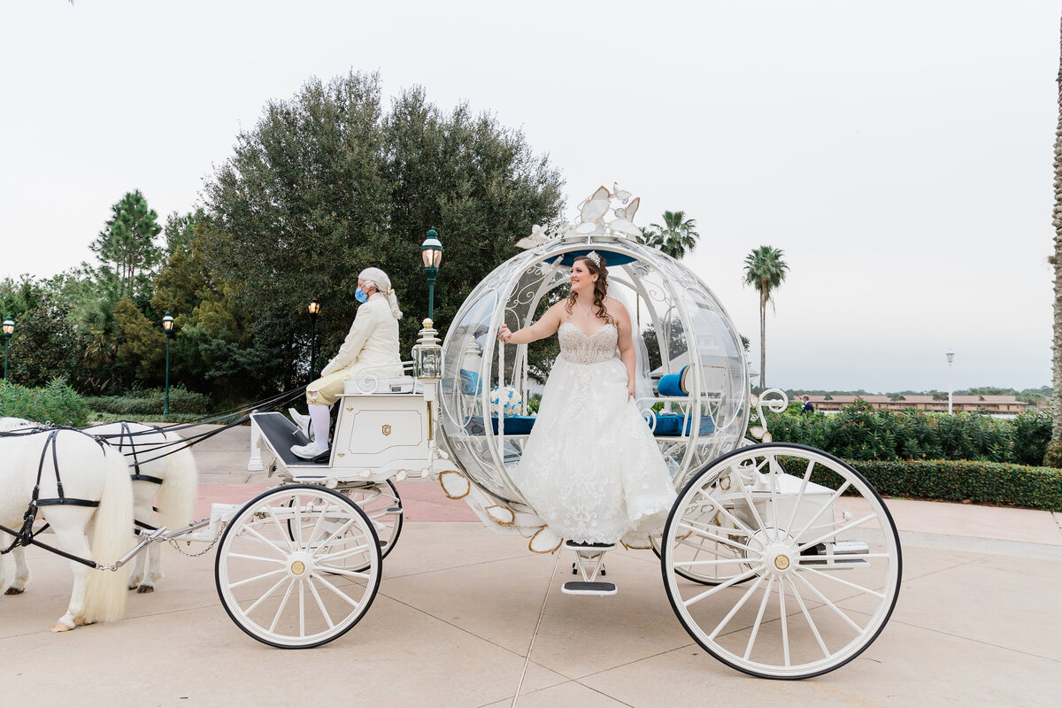 Bride getting out of Cinderella's carriage at Disney wedding