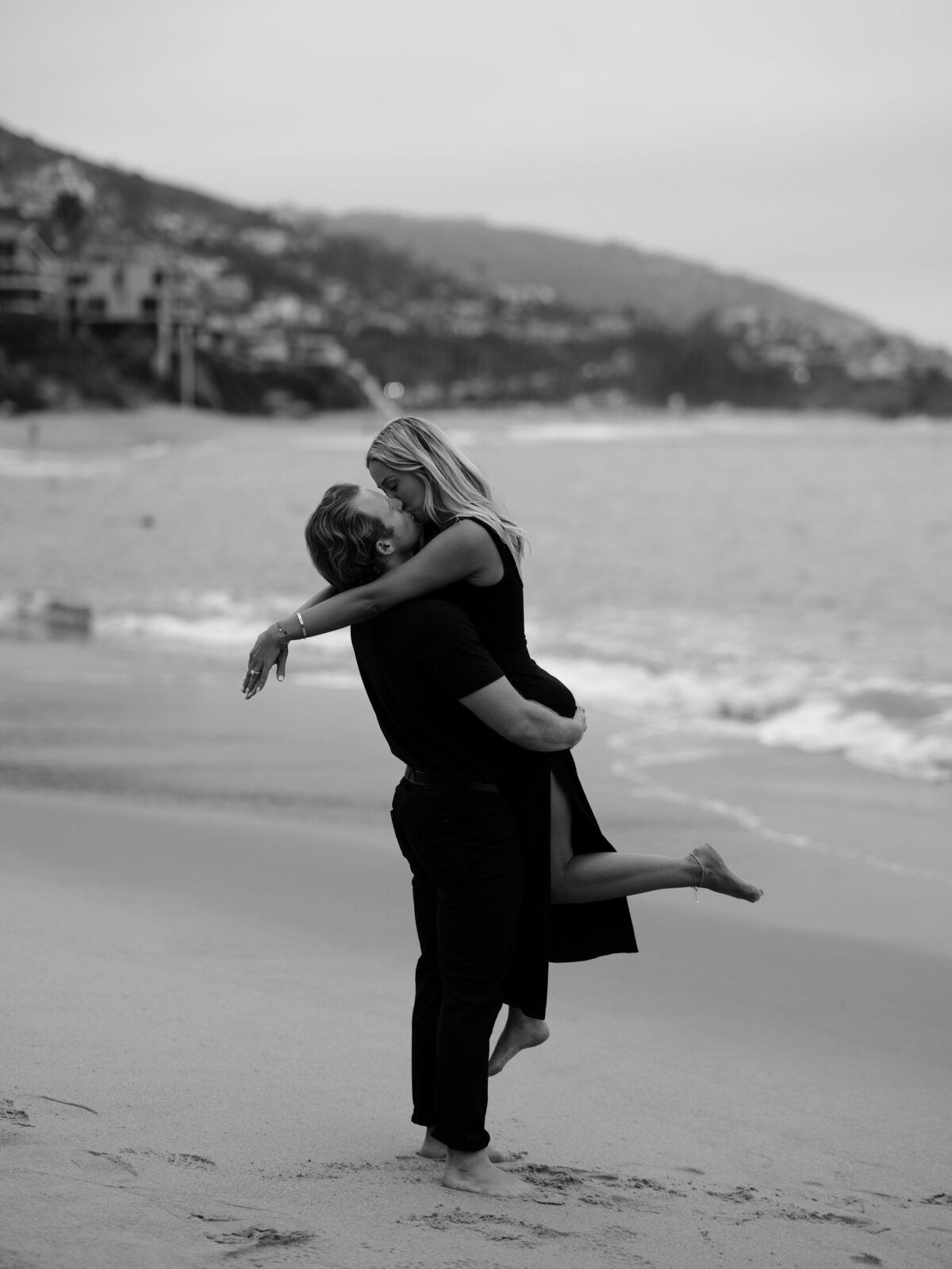 man holding woman up on the beach for California engagement shoot