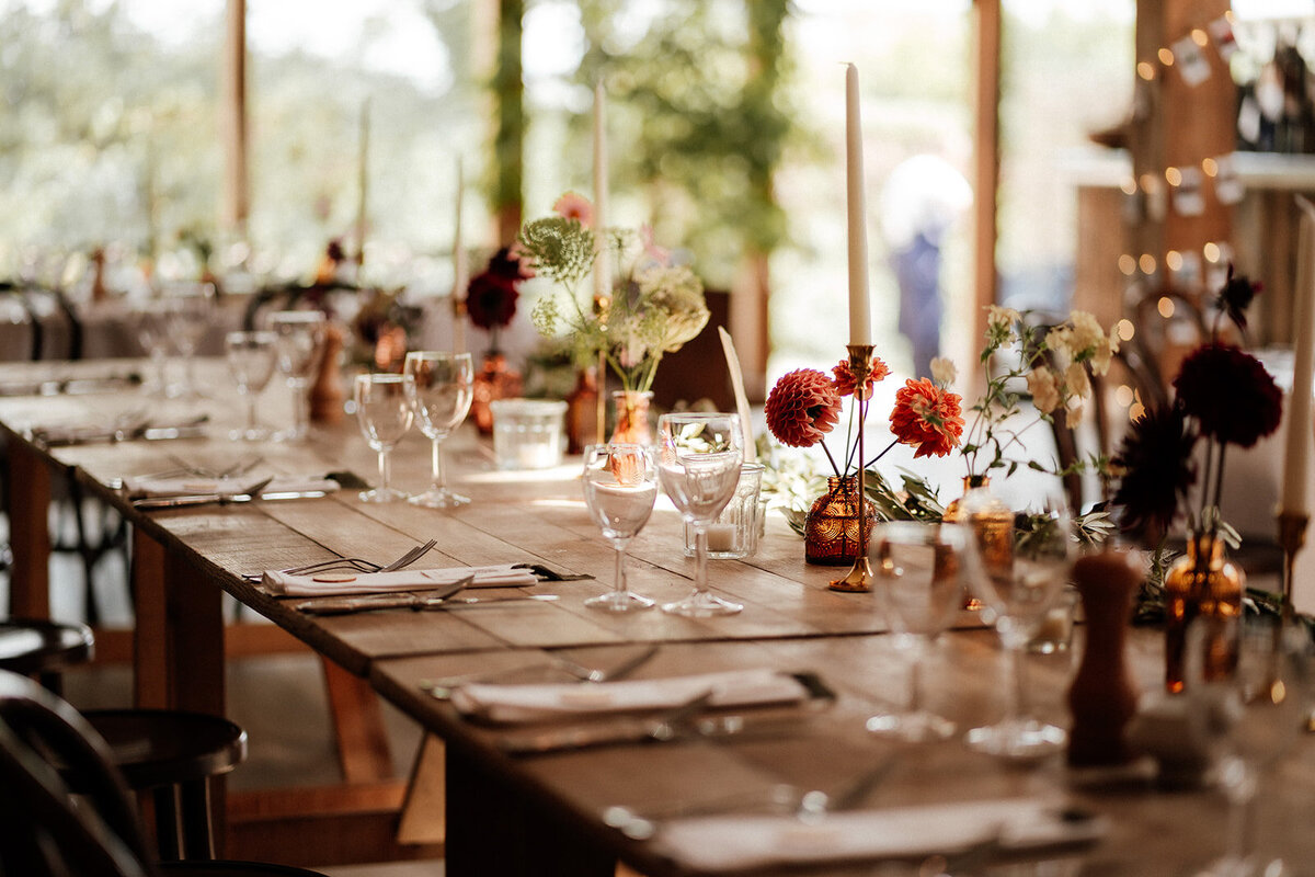 Bud vases of flowers for the top table at Cripps Barn with gold candle sticks 