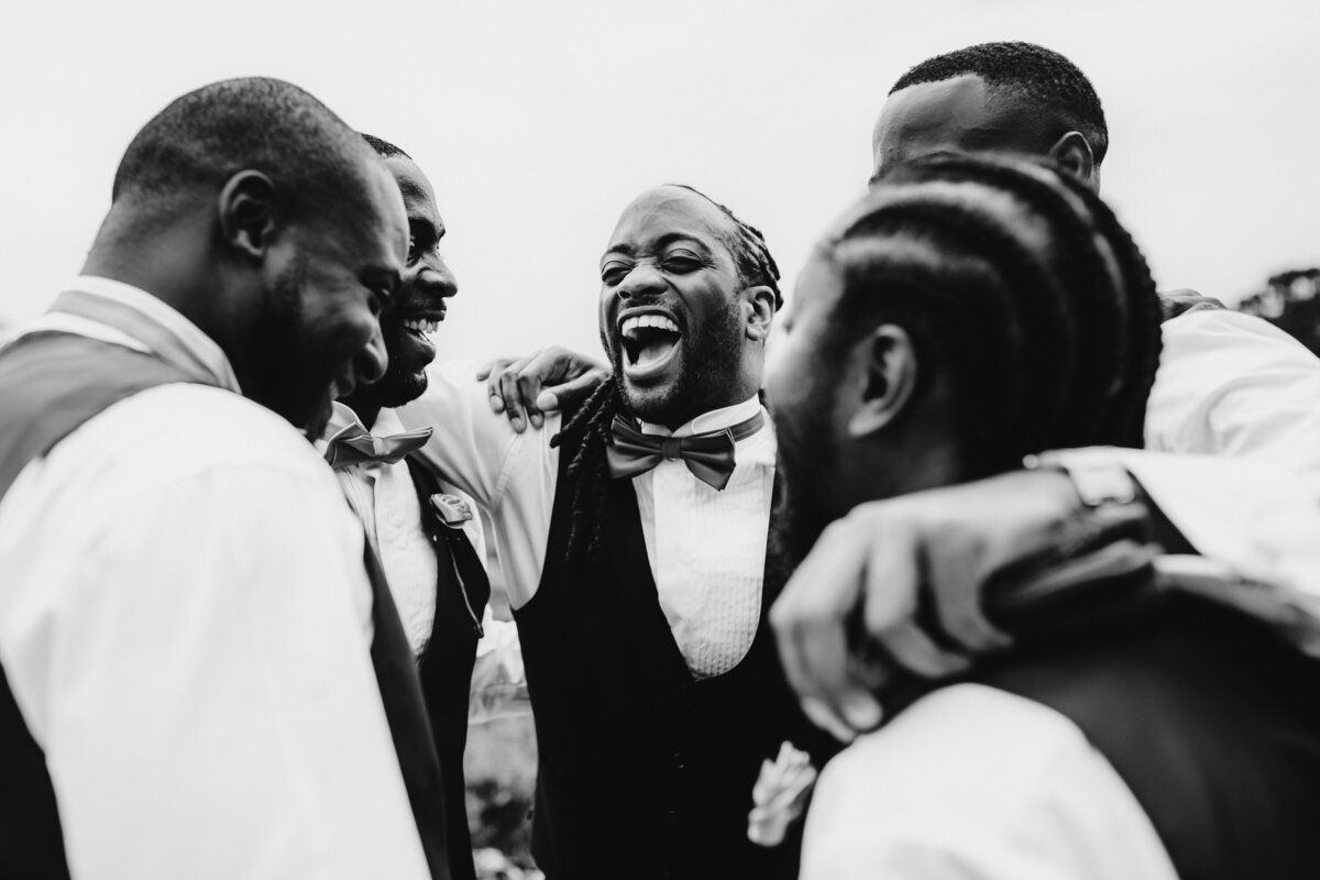 Black and white photo of groomsmen laughing together