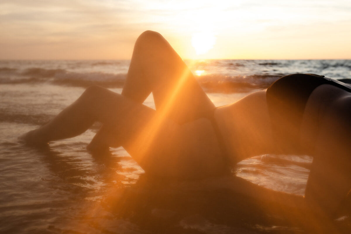Bare silhouette of a woman against the backdrop of a golden sunset at the beach
