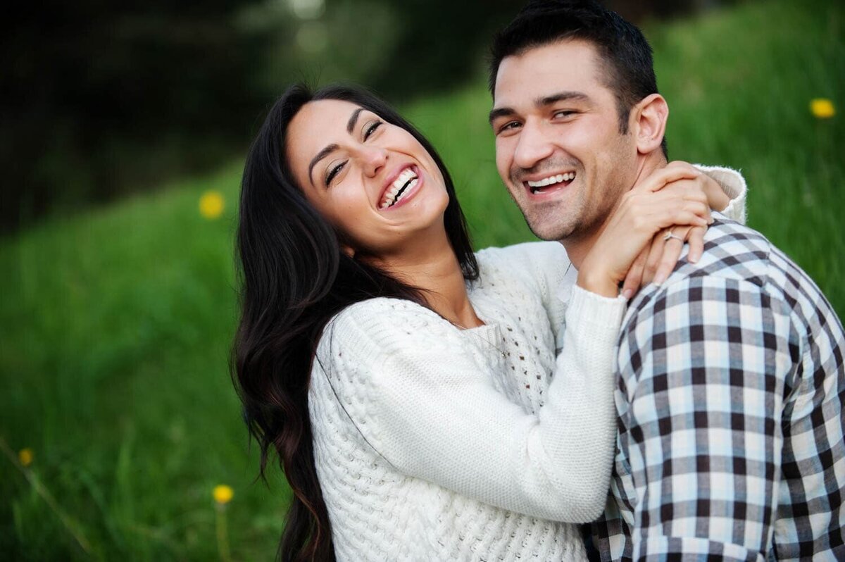 a man and woman hug and laugh while playing in the grass