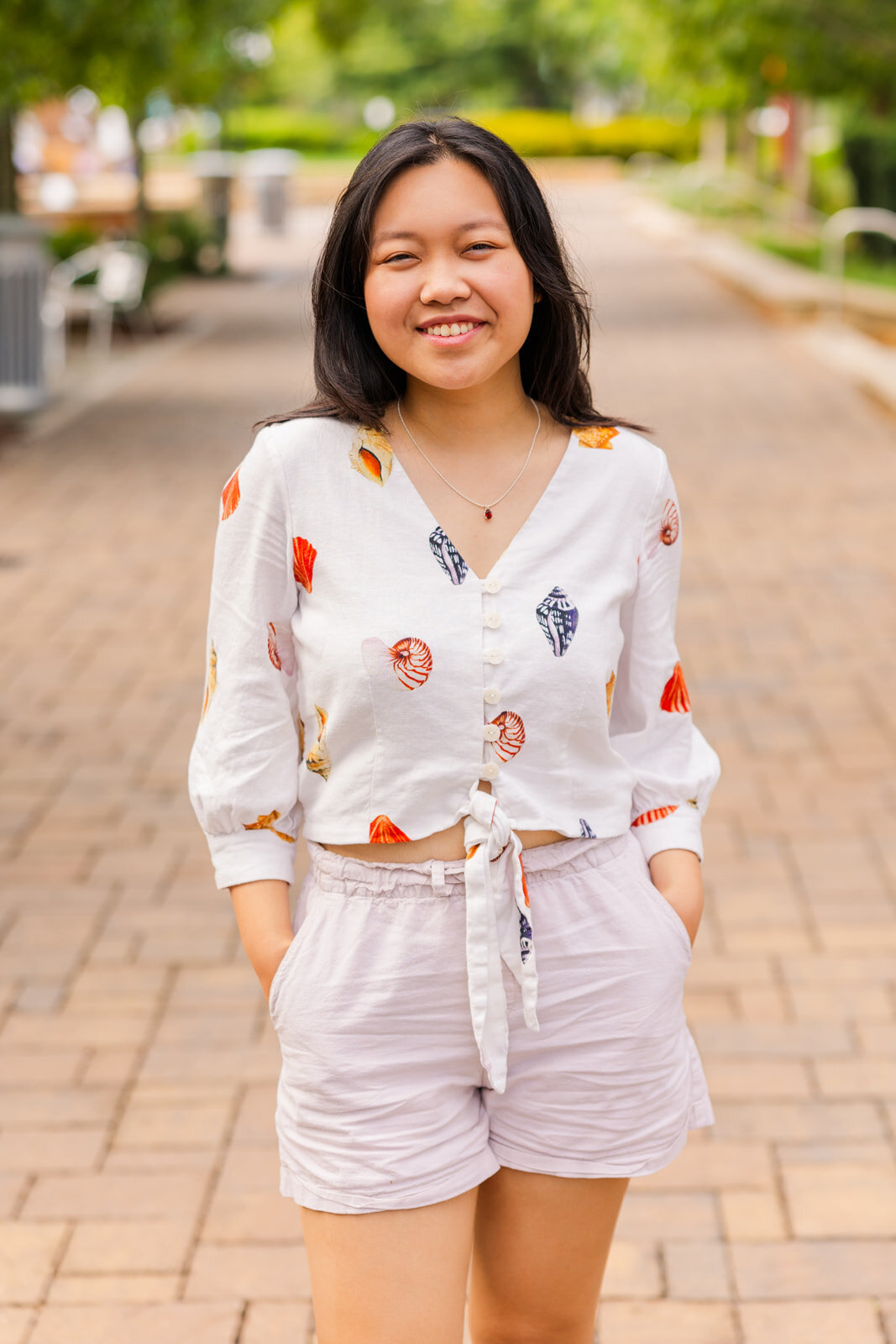 senior girl standing on the middle of a urban path hands in pockets and smiling at the camera during portraits photoshoot