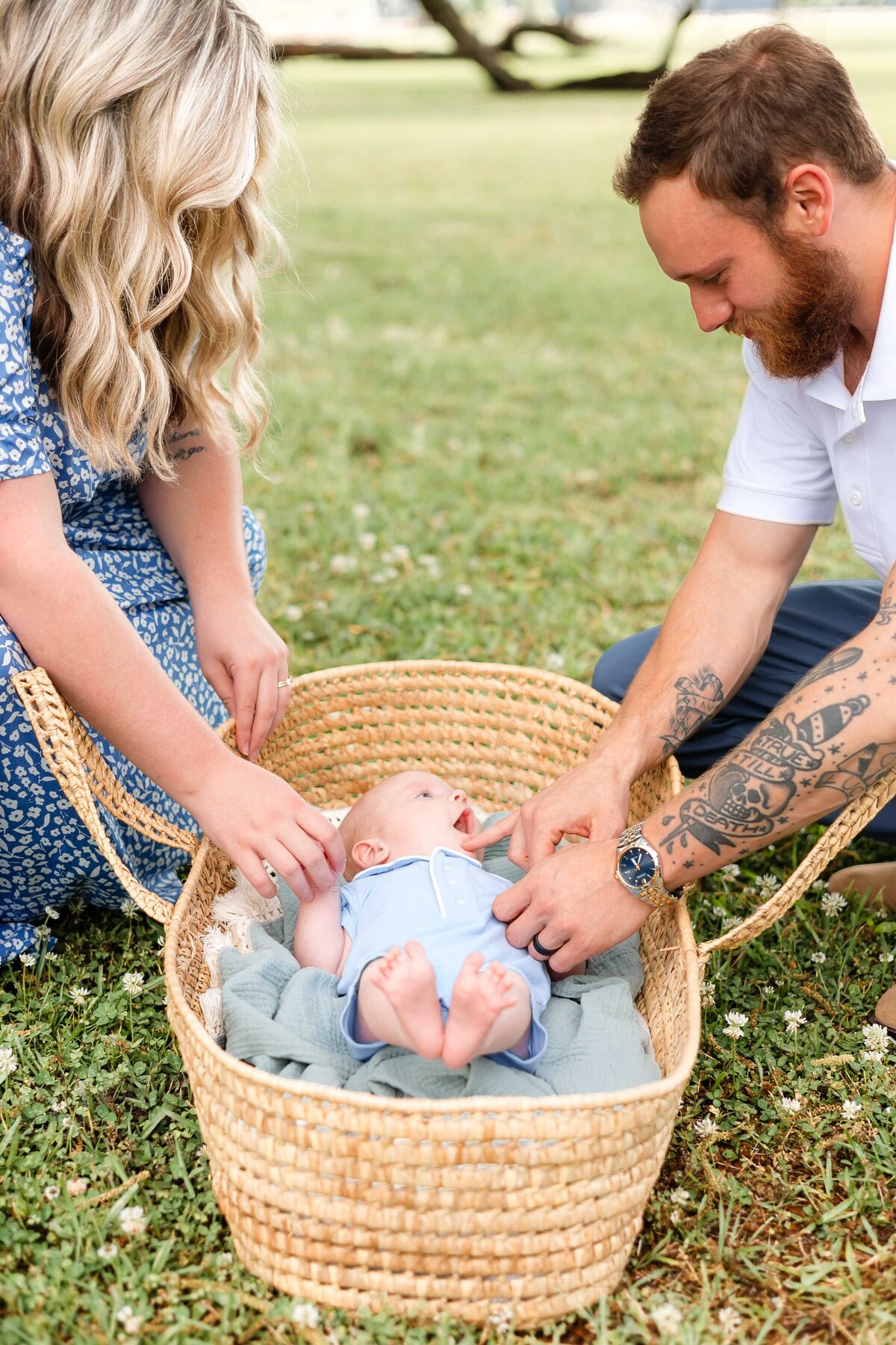 young family playing with 4 month old who is laying in a moses basket outside. sweet moments with dad
