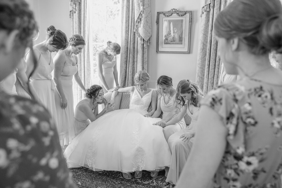bride prays with her bridesmaids and mother