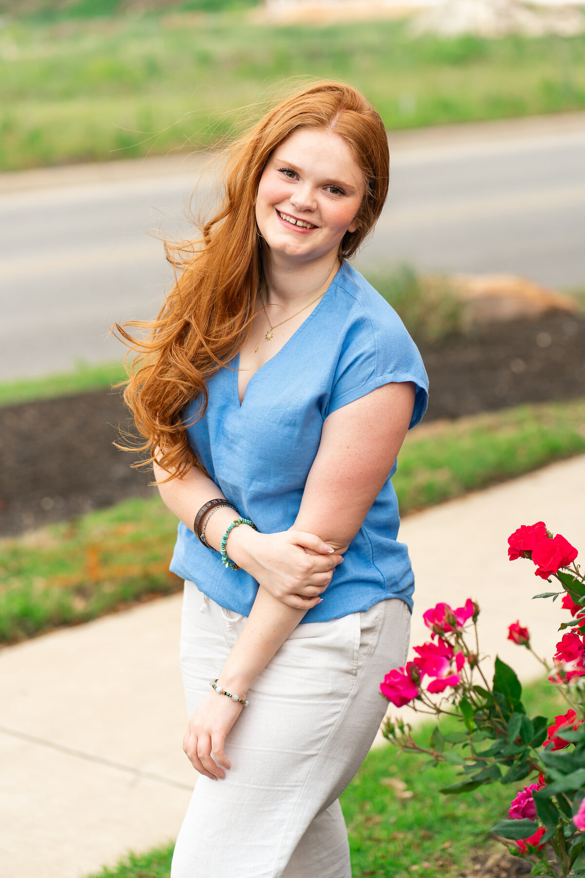 Red head high school senior girl posing in flowers for graduation photos. Austin Senior Graduation.