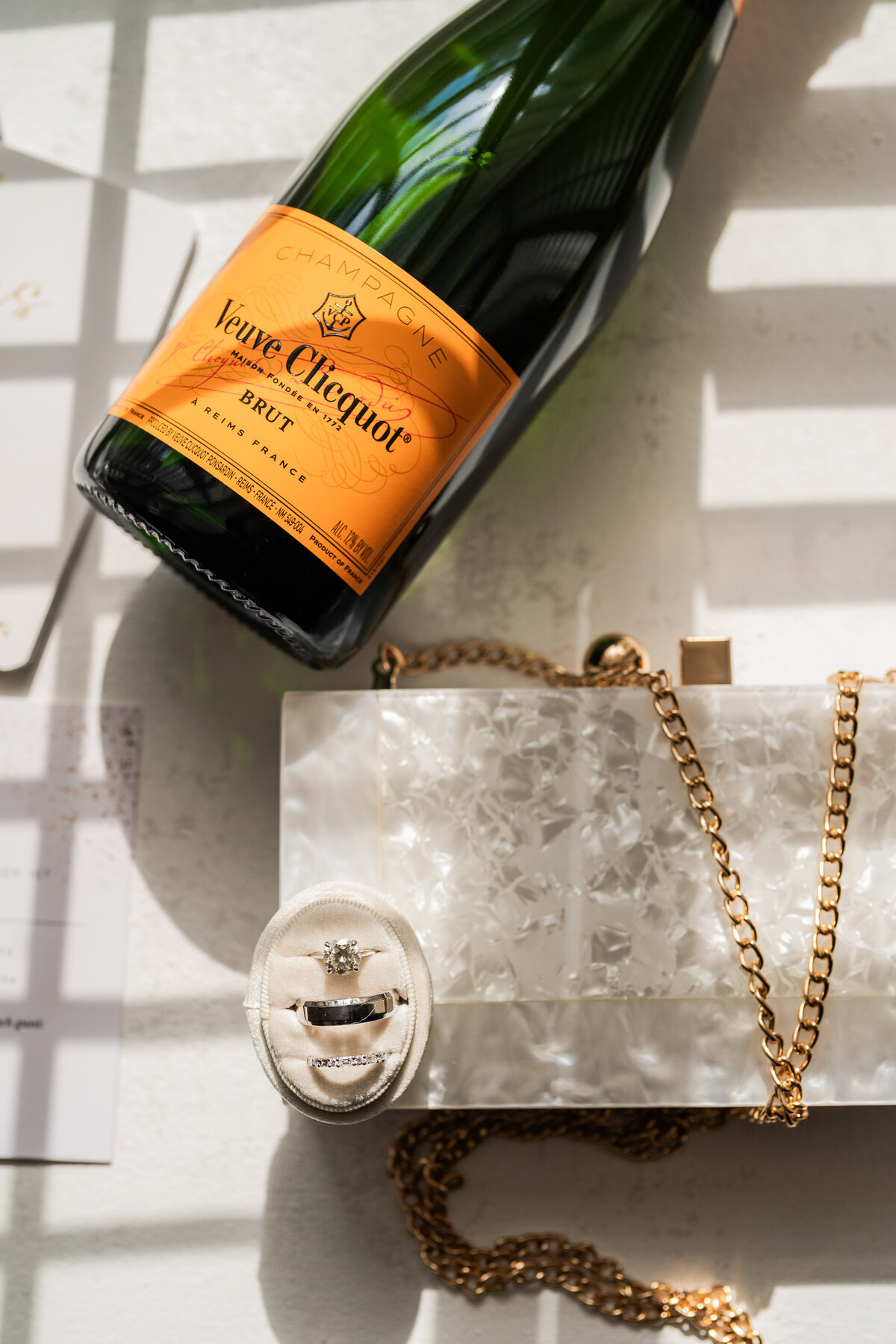 Photo of brides wedding details including rings purse and veuve clicquot champagne bottle