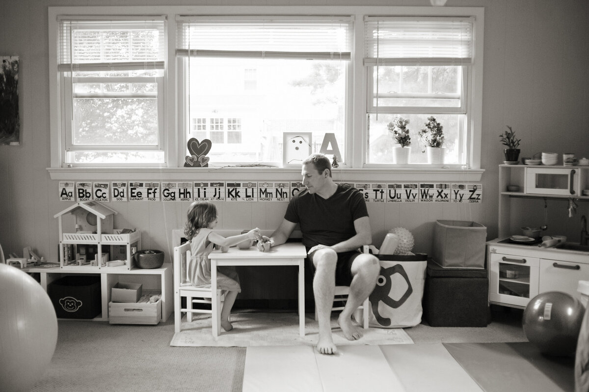 A parent sitting with their small child at a table while they play 