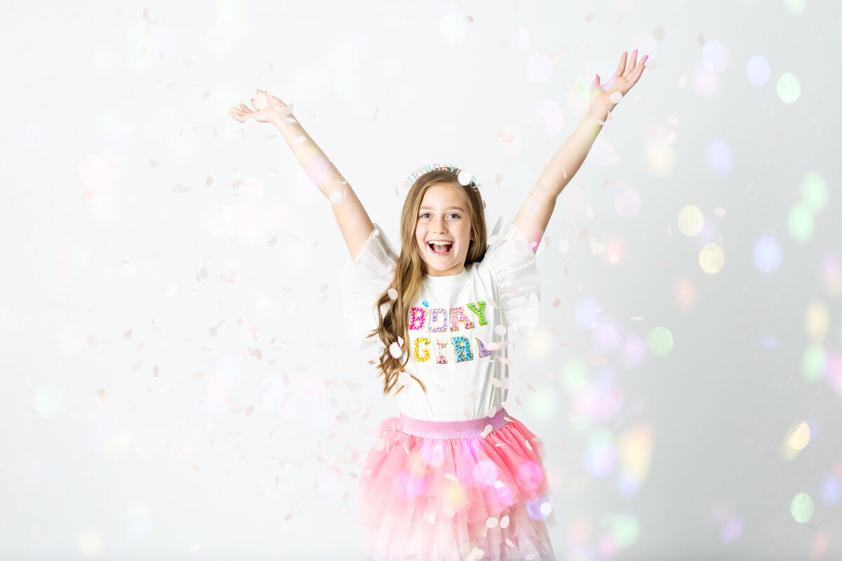 Excited birthday girl celebrating with confetti and colorful decorations, captured in a playful session by Victoria Lee Photography in Canton, GA.