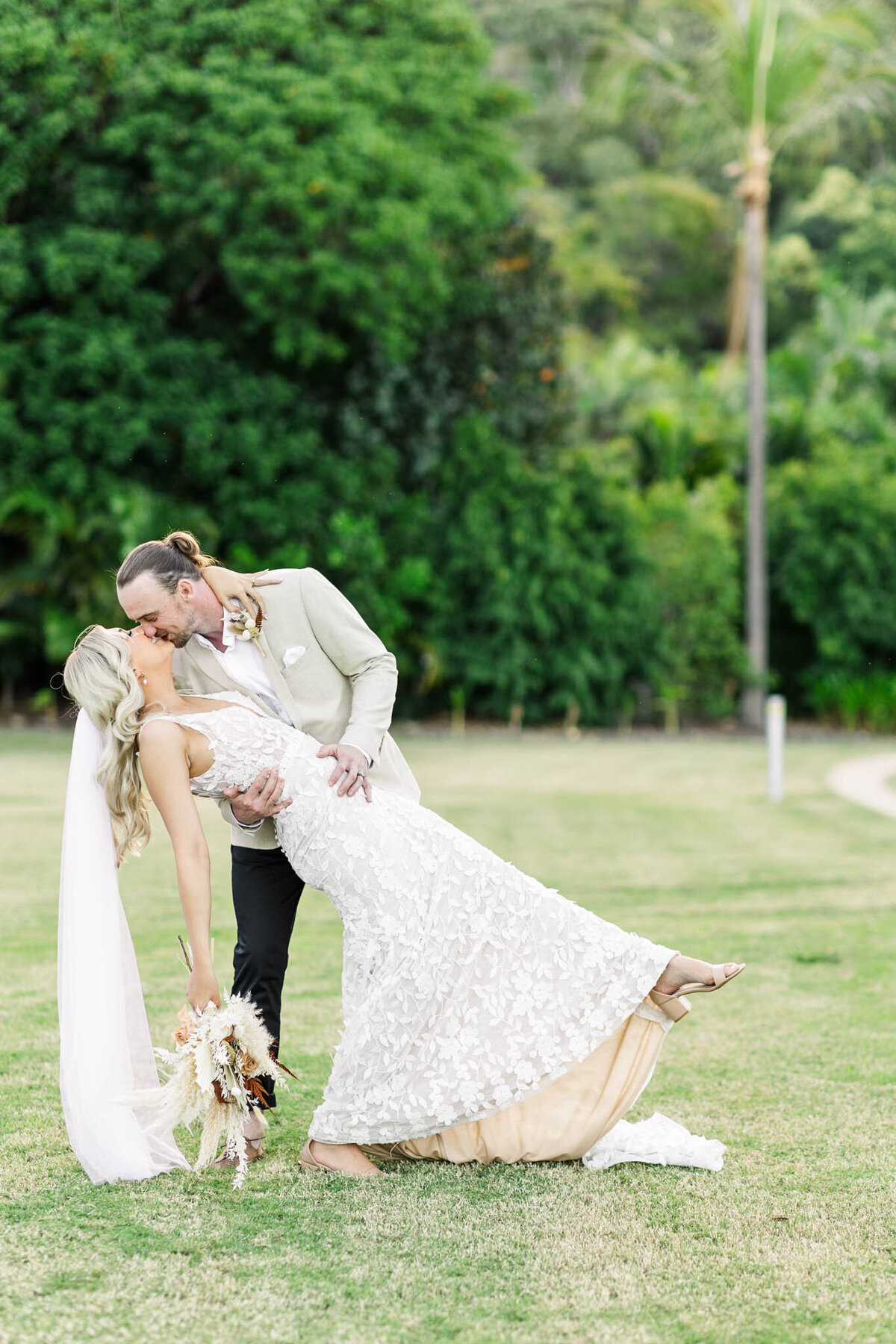 Groom dips his new bride and kisses her at their Whitsunday wedding by Alyce Holzy