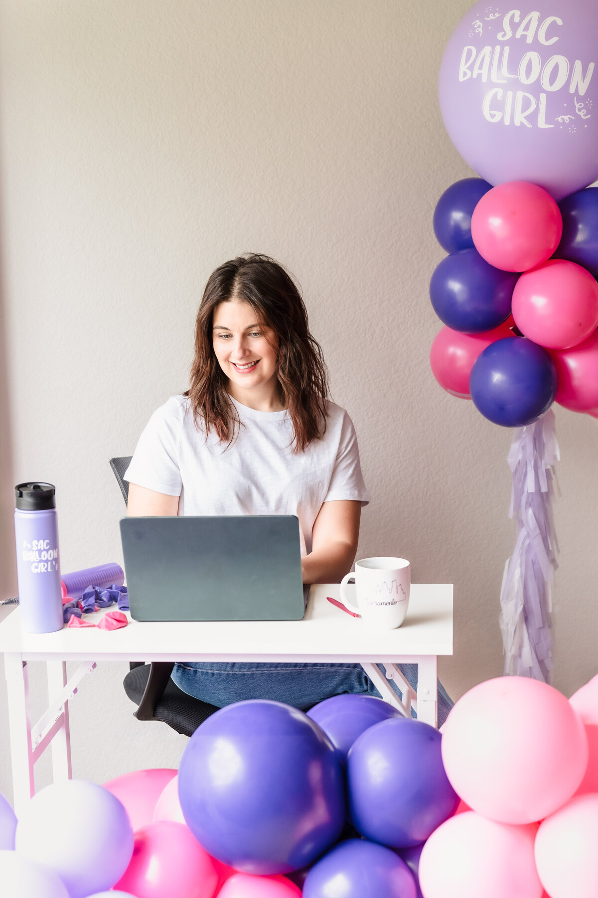 woman working in her desk among pink and purple balloons