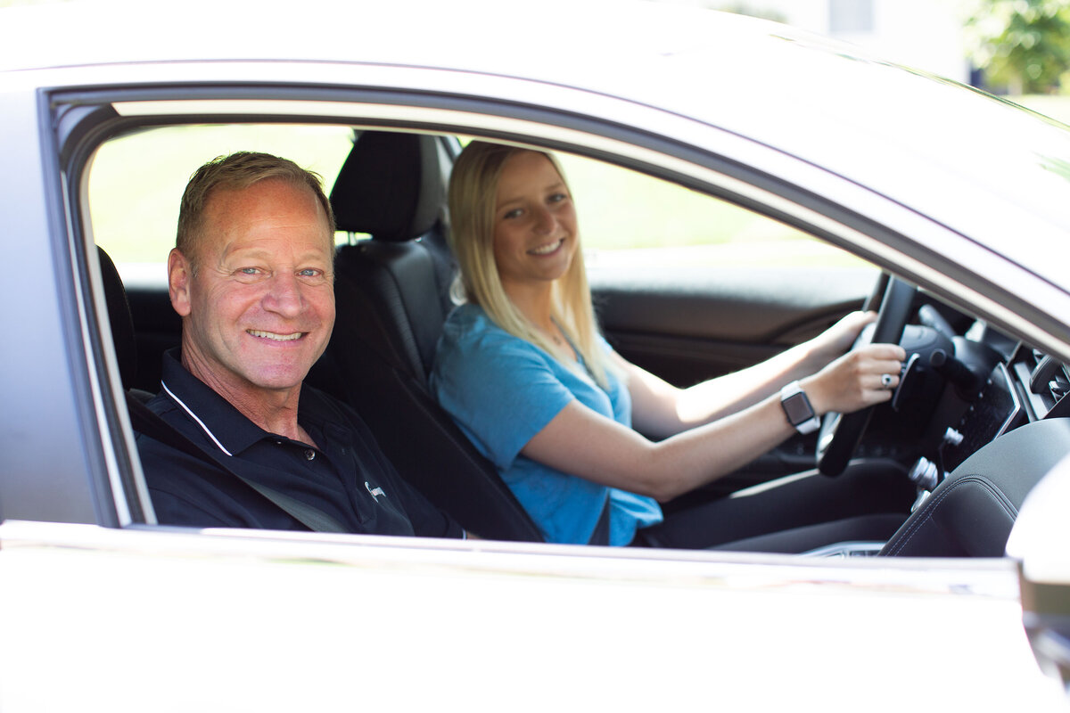 Driving coach and student in vehicle looking at camera