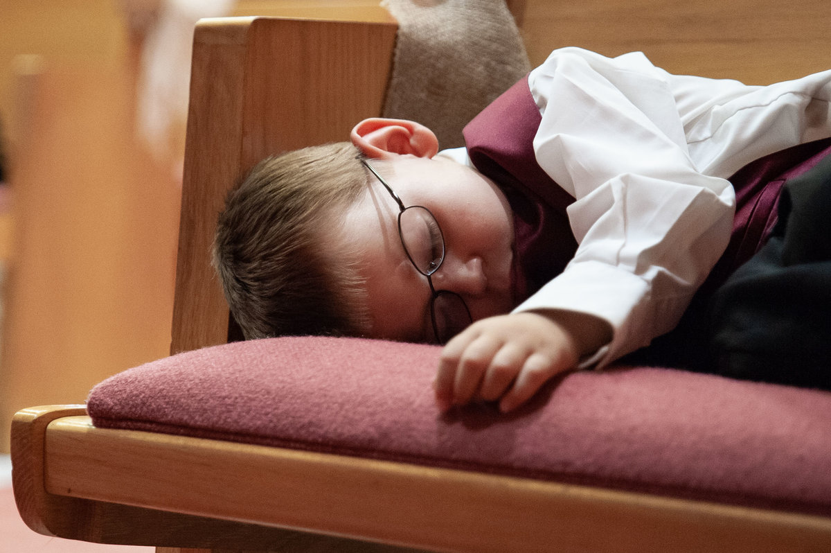 child sleeps on church bench during ceremony