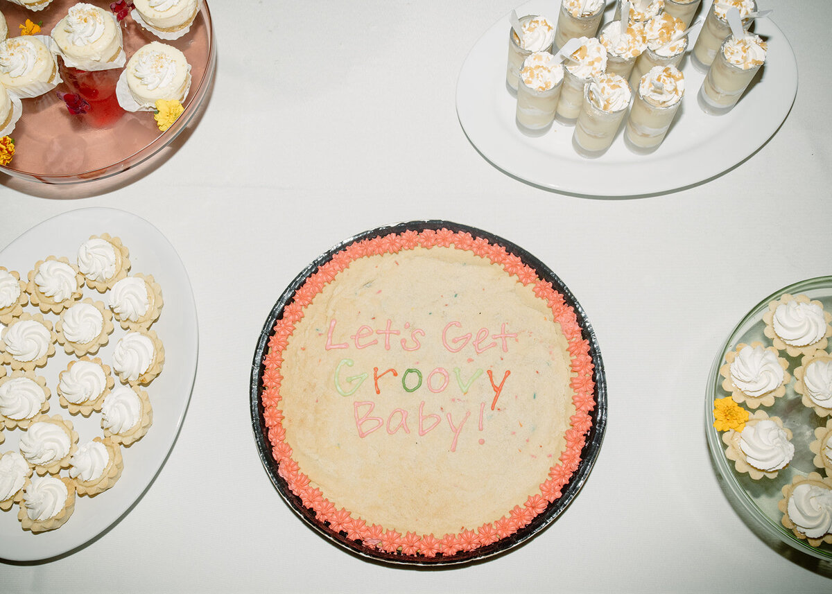 Mini wedding reception desserts and a cake that says Let's Get Groovy Baby