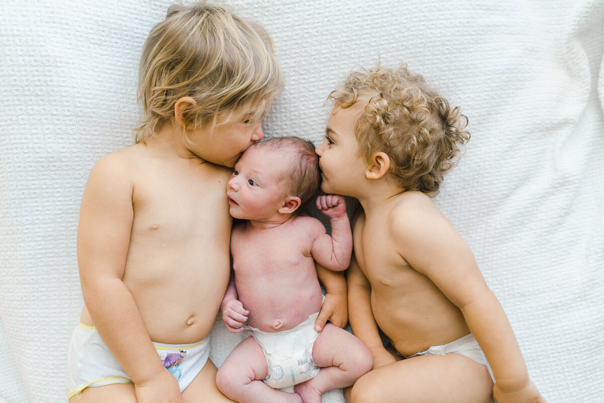 newborn baby and siblings snuggled up