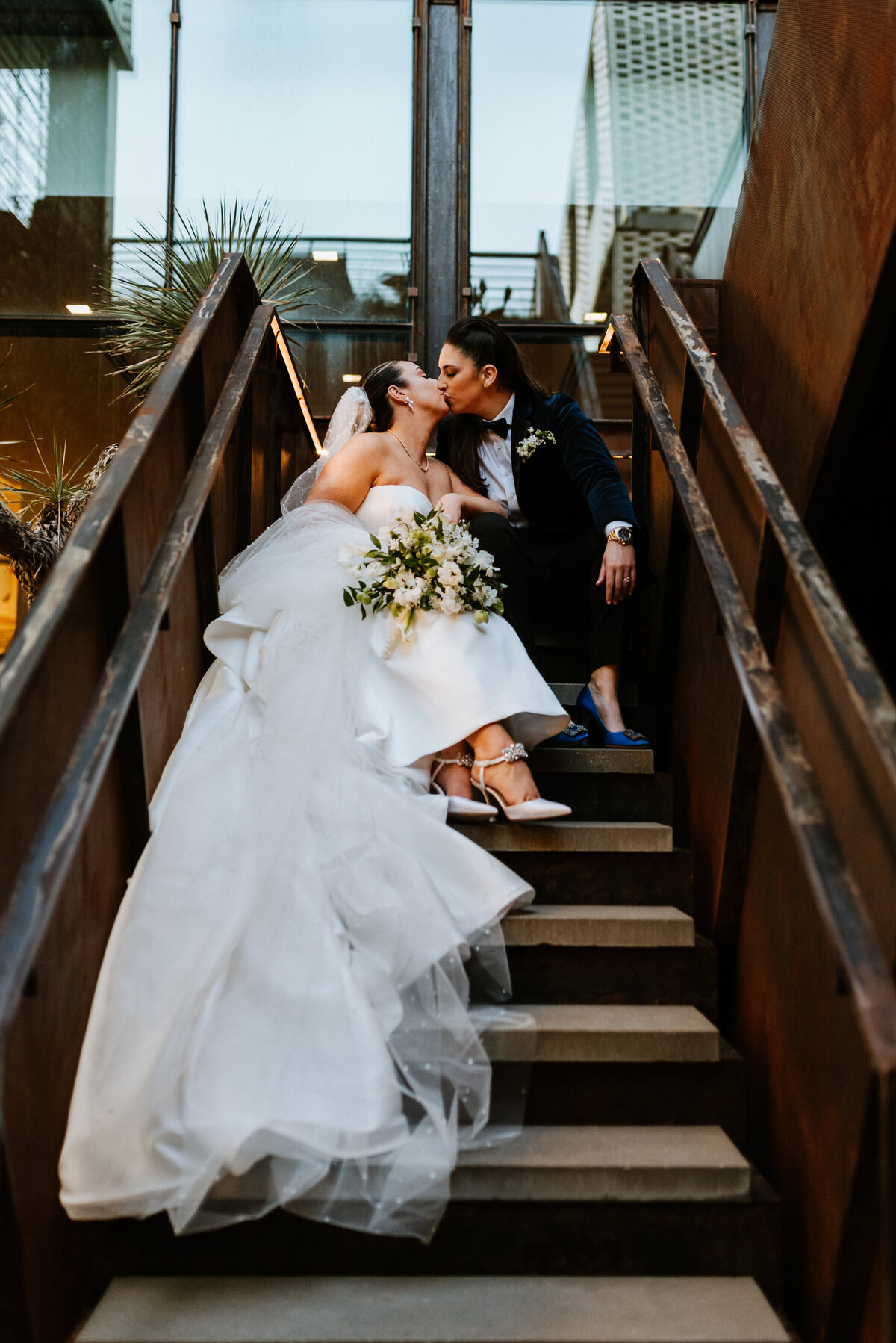 brides kissing on staircase sitting down