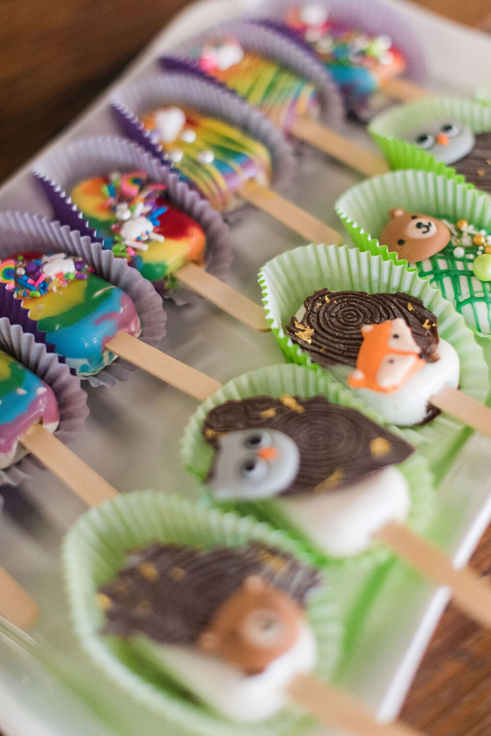 Woodland-themed dessert cake pops featuring rainbows and woodland animals, designed for a baby boy shower.