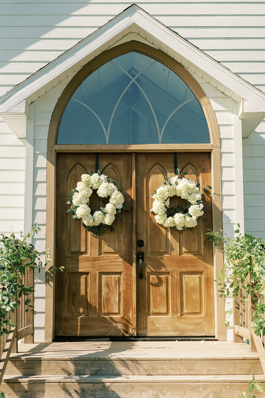 wooden church doors decorated with white floral wreaths